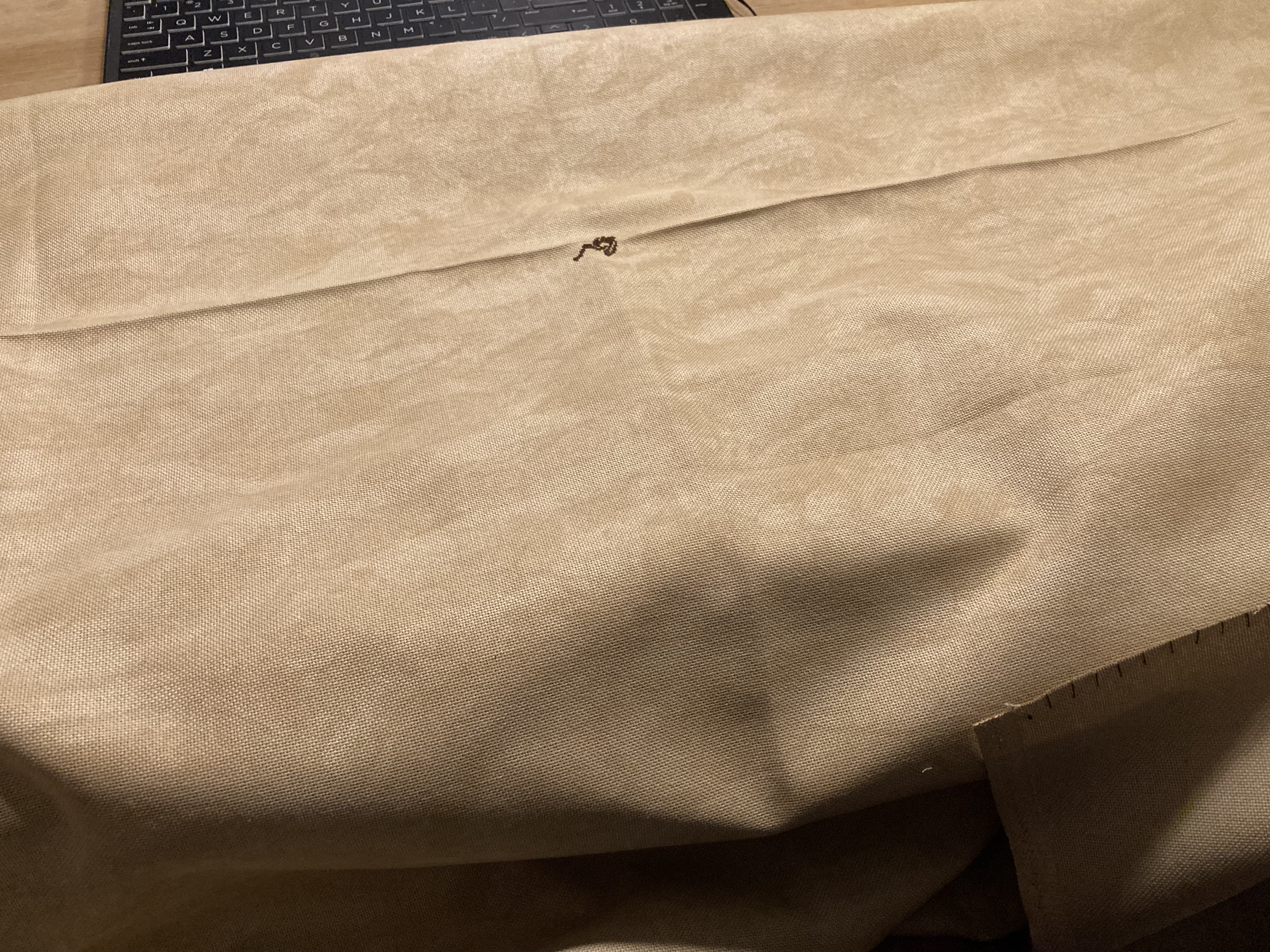 A large piece of fabric with small splotch of stitches in the middle