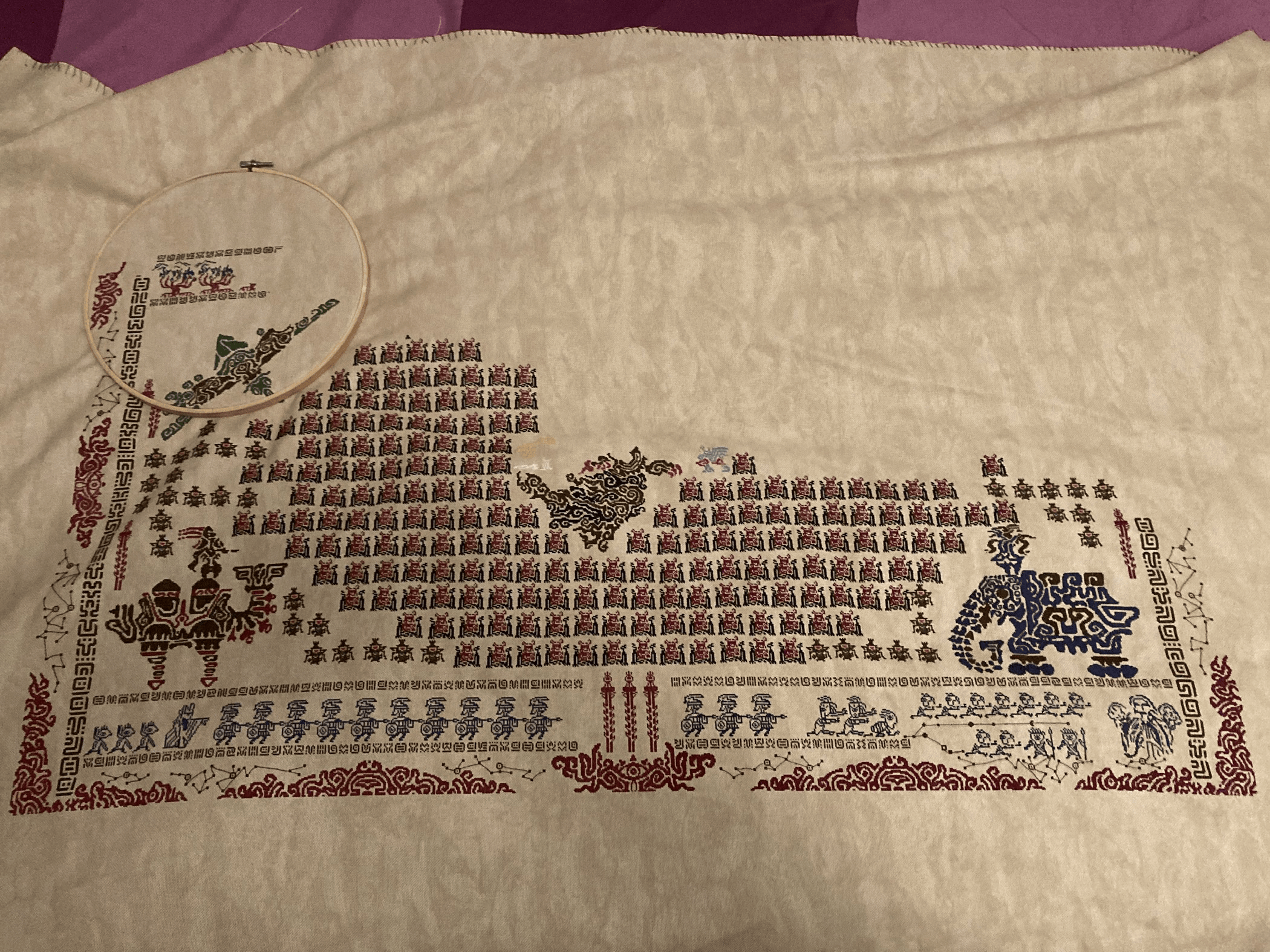 A large piece of fabric. A little less than 3/4 of an elaborate pattern is stitched onto it